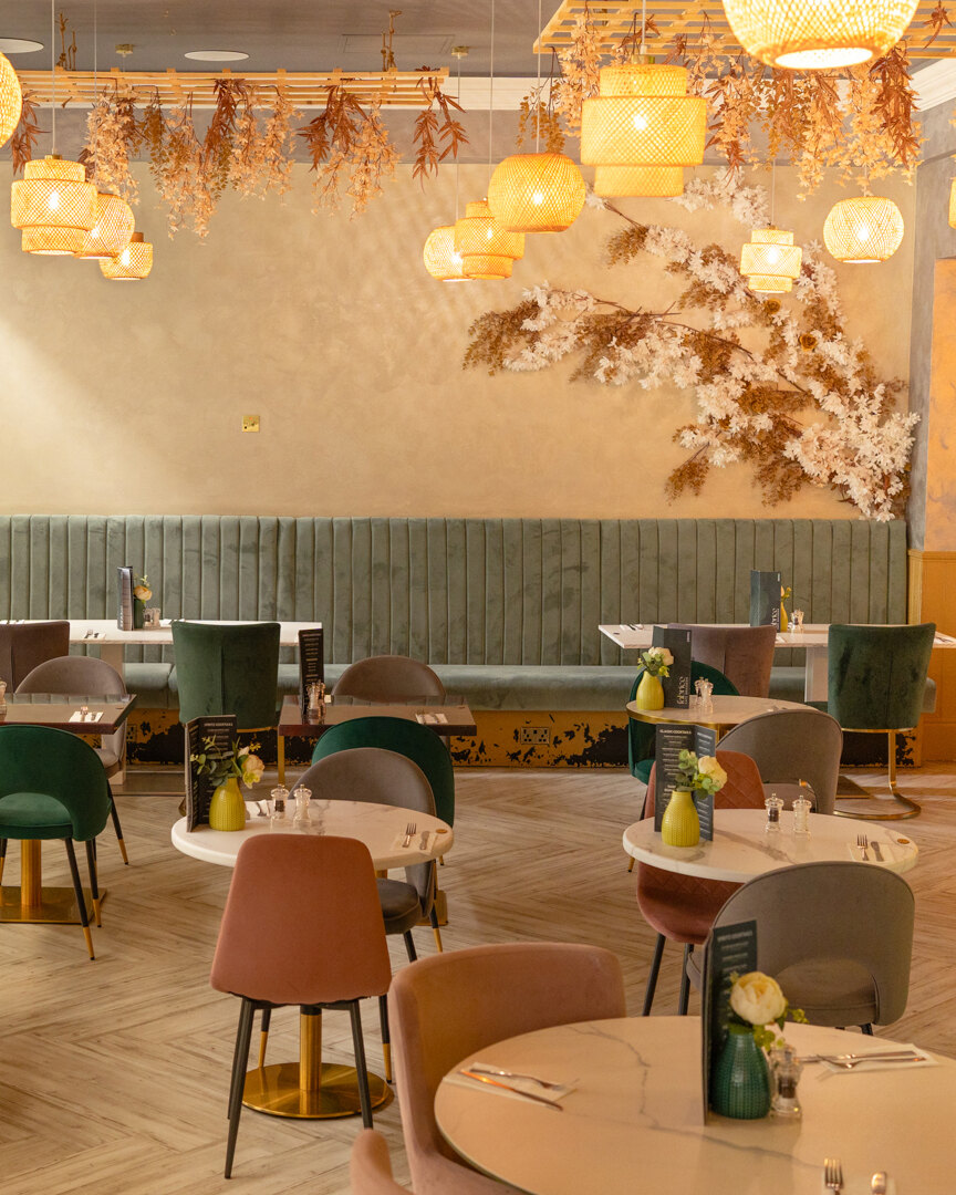The dining room at Fabrice Brasserie, banquette seating and rattan pendants